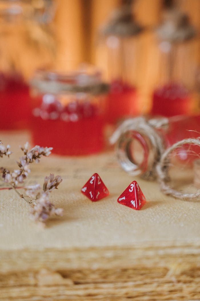 creative-01 Close-up view of red tetrahedral dice amidst rustic jars and burlap on a natural surface.