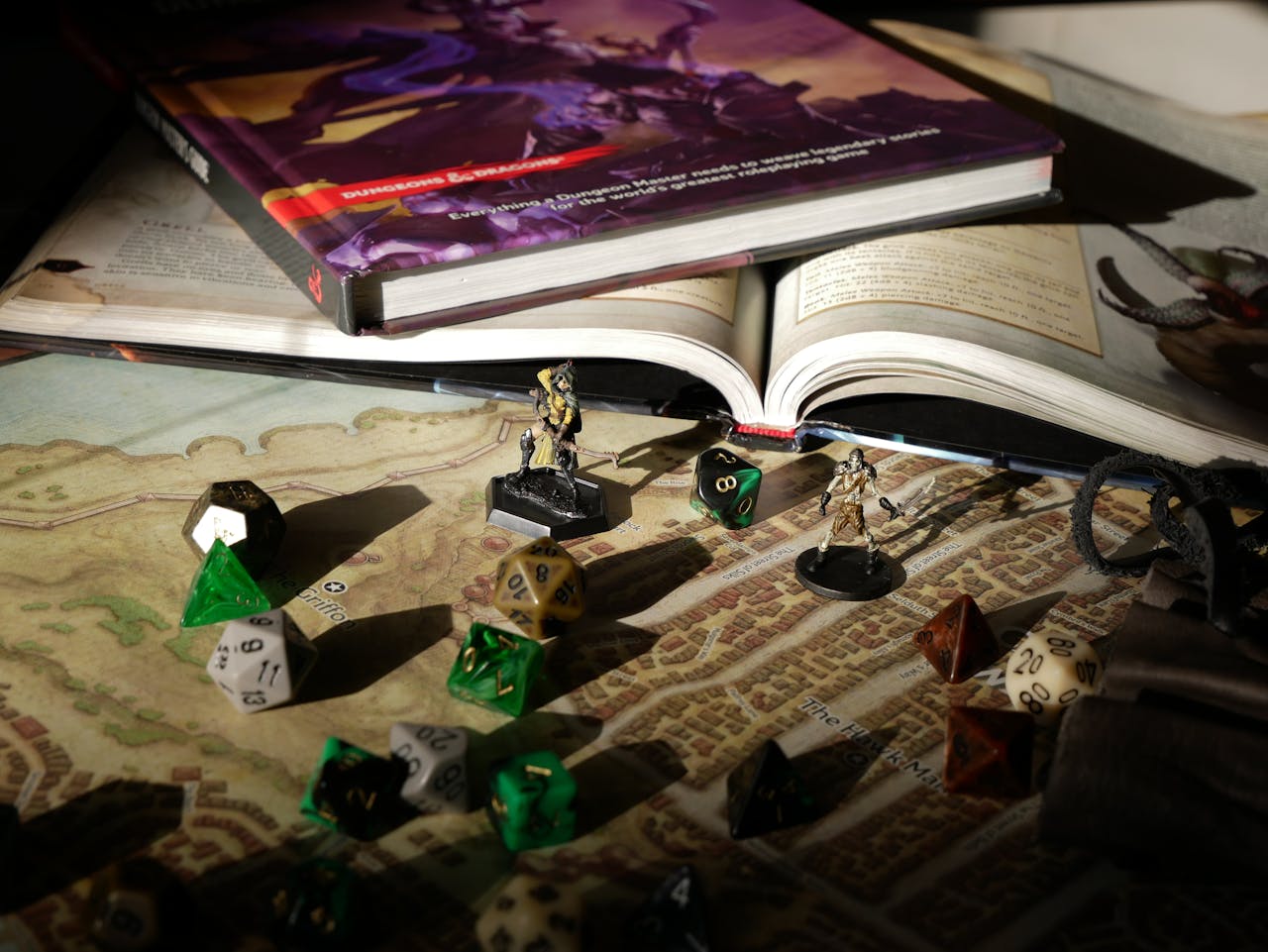 creative-03 Close-up of tabletop RPG setup with books, dice, and figurines on a map.