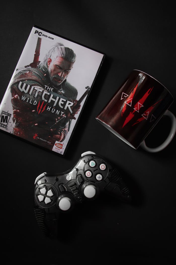 creative-02 Flat lay of The Witcher Wild Hunt game with controller and themed mug on black background.