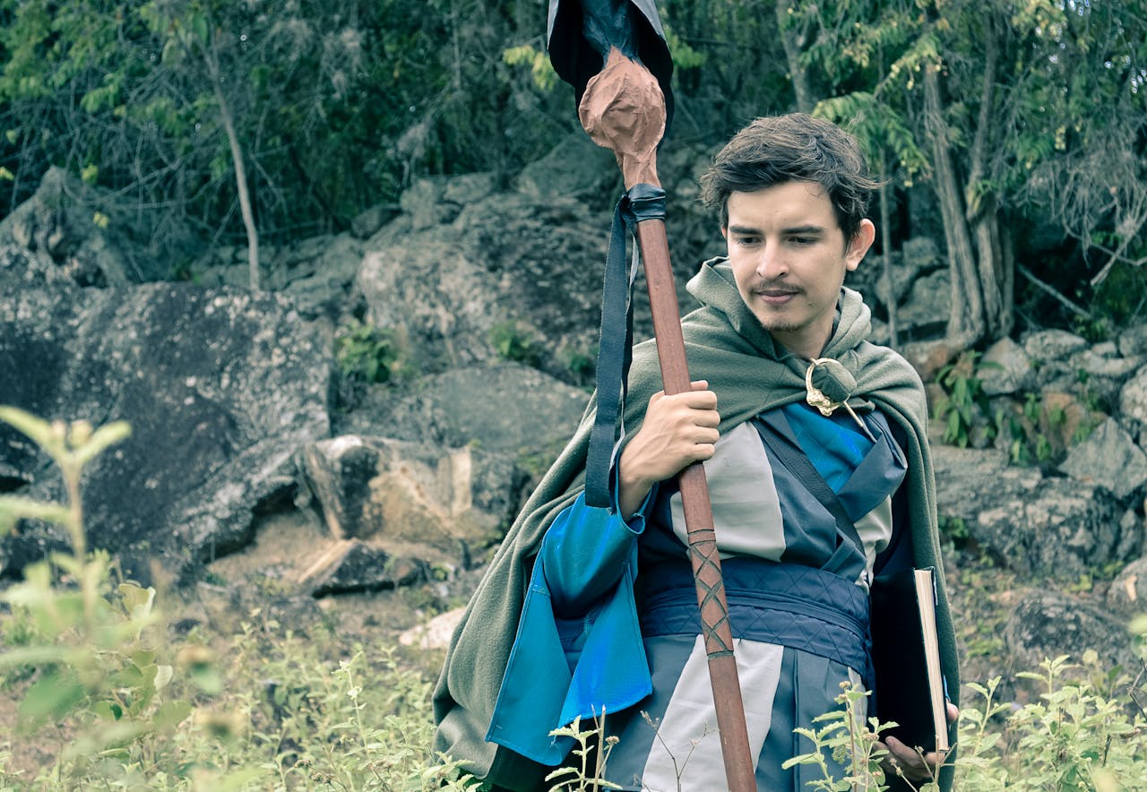 our-story Man wearing medieval cosplay costume holding staff in a forest setting in Colombia.
